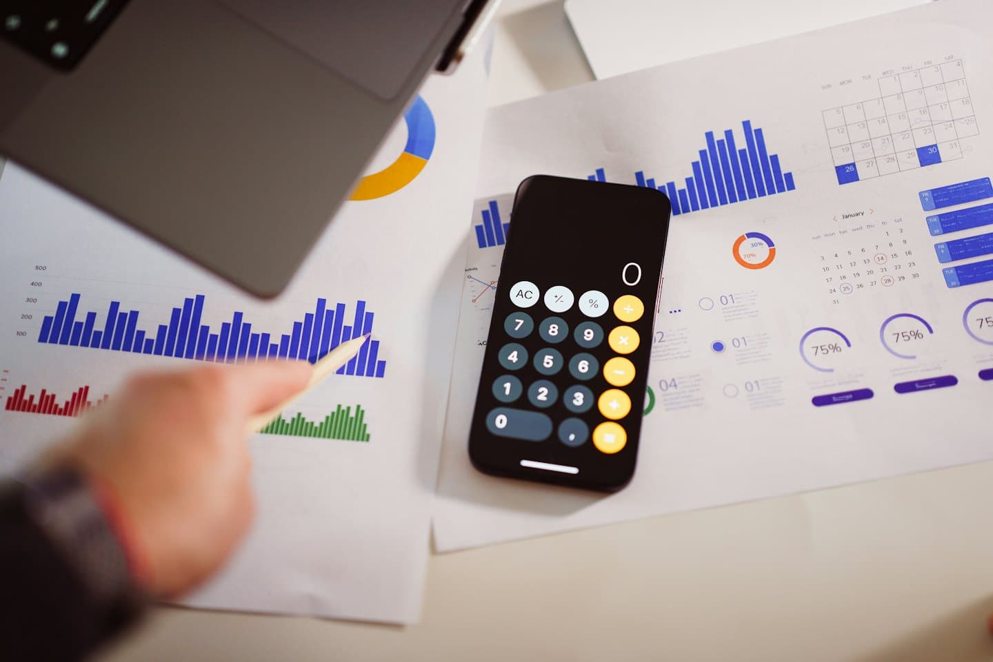 Mano che indica un grafico a barre con laptop e smartphone.